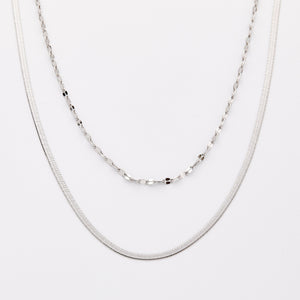 Silver necklace set with a herringbone chain and a flutter chain, displayed on a light background.