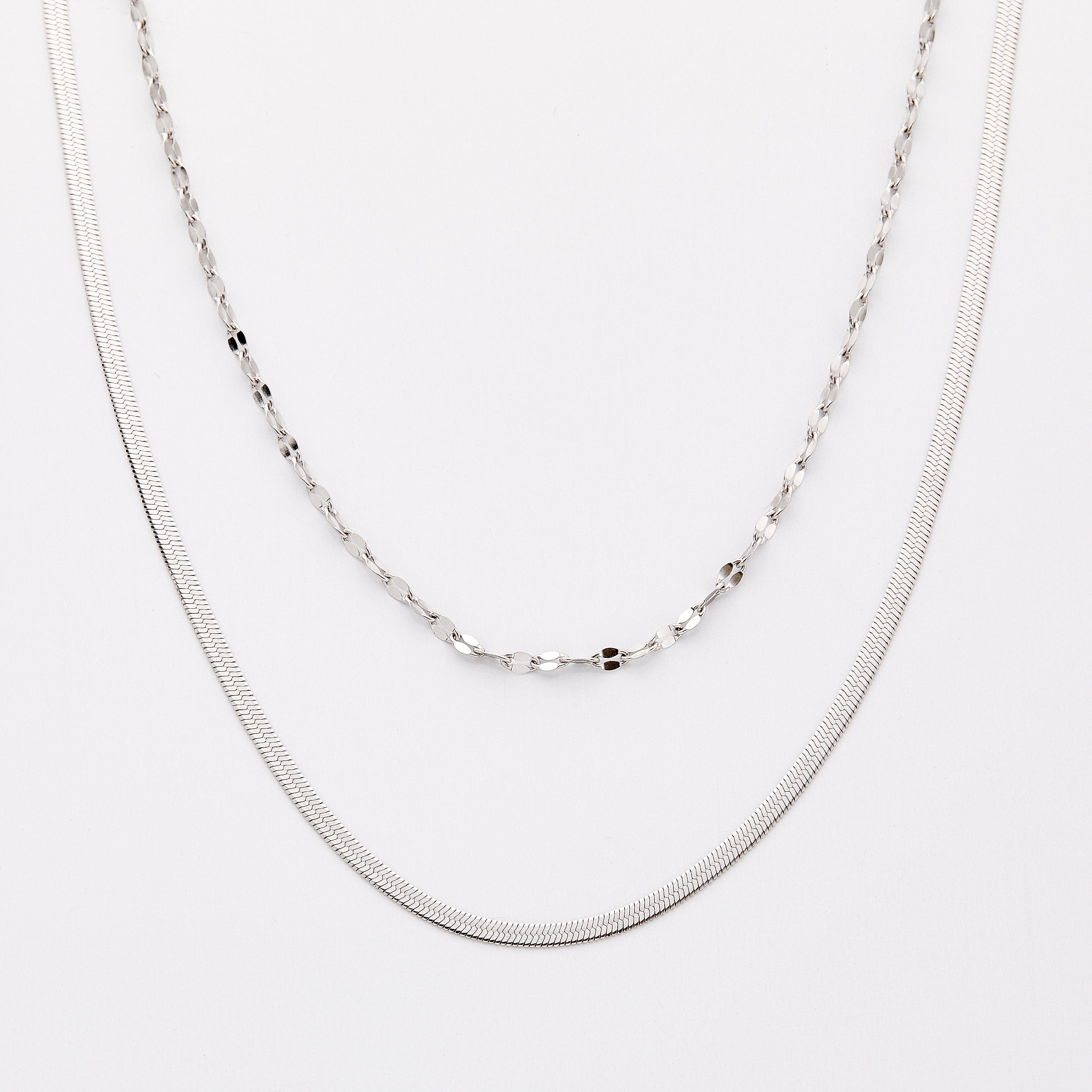 Silver necklace set with a herringbone chain and a flutter chain, displayed on a light background.