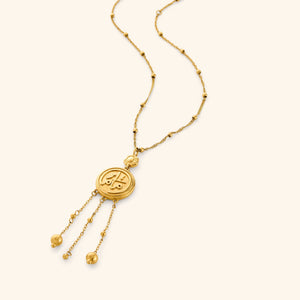 18k gold plated necklace that features a coin pendant stamped with ماما (Mama) in Arabic, suspended from a beaded chain with three strands falling beneath, stamped with a miniature floral at the top.
