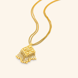 Gold dancing kite necklace with a diamond pendant featuring floral engravings and dangling chains with small gold beads.