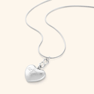 Photo of a silver thin chain necklace that features a  puffed heart pendant is engraved with the words “Free Palestine” in Arabic (فلسطين حرة).