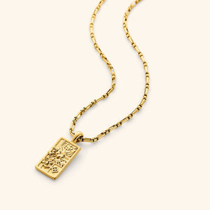 In the photo, a rectangular 18K gold plated pendant that features design Inspired by the mosaic patterns of Damascus found in the mosques and courtyards, blooming with the national flower of Syria: the jasmine on a gold chain.