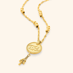 Flat lay of an 18k gold plated necklace that features Love, حب, etched in Arabic, designed with vintage coin jewelry in mind, this piece is adorned with delicate dangling orbs.