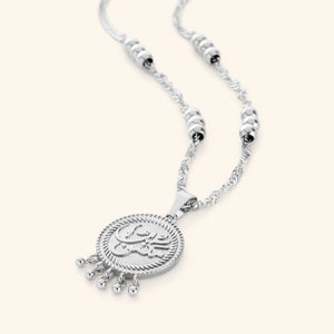 A silver  necklace that features a coin pendant with the inscription: مكتوب—"Maktub", twisted chains, burst orbs, and the delicate dangling dots add movement and elegance, 