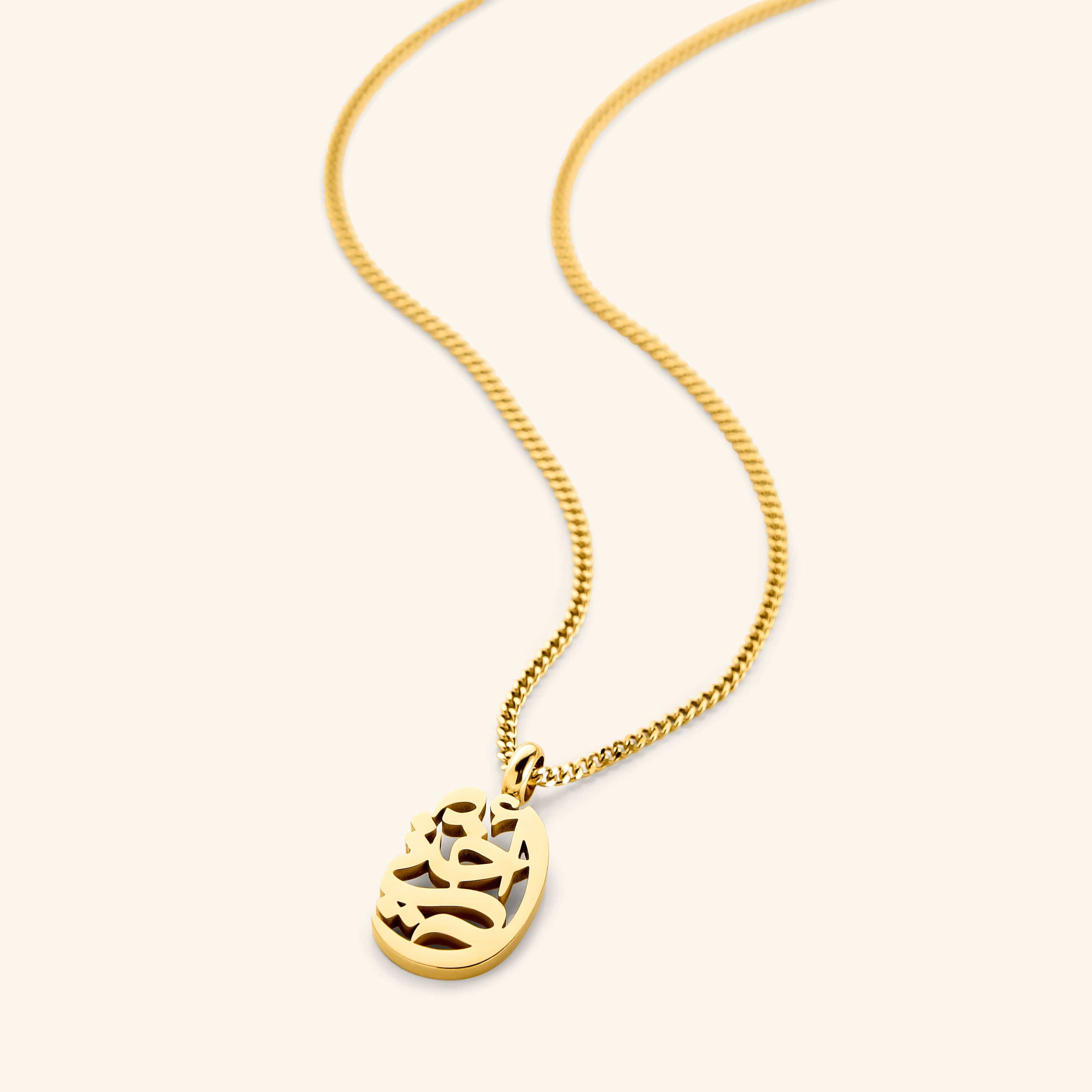 A close-up of the My Sister Oval Necklace in 18K gold plating. The oval pendant features the Arabic word "أختي" ("Ukhti" – My Sister) engraved in elegant calligraphy, suspended from a delicate gold curb chain.