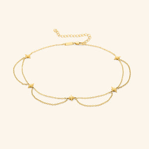 Flat lay of the 18k gold plated necklace that features north stars all along the chain, drooping chains connecting each one.