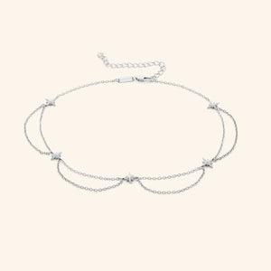 Flat lay of the silver necklace that features north stars all along the chain, drooping chains connecting each one.