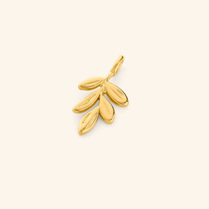 Close-up of a gold olive branch charm featuring five oval leaves with engraved detailing, set against a soft beige background.
