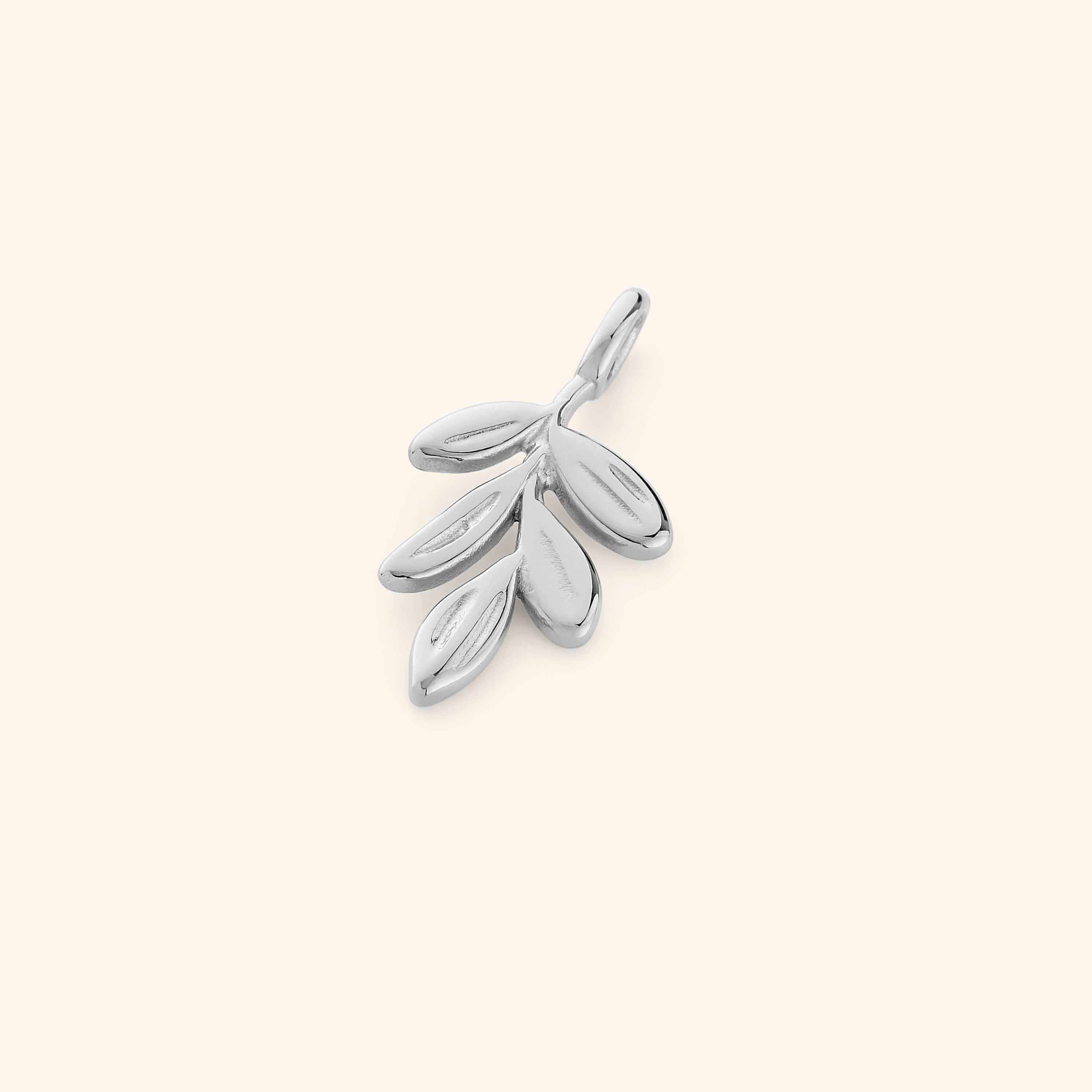 Silver olive branch charm featuring five smooth, oval leaves with subtle engravings, displayed on a beige background.