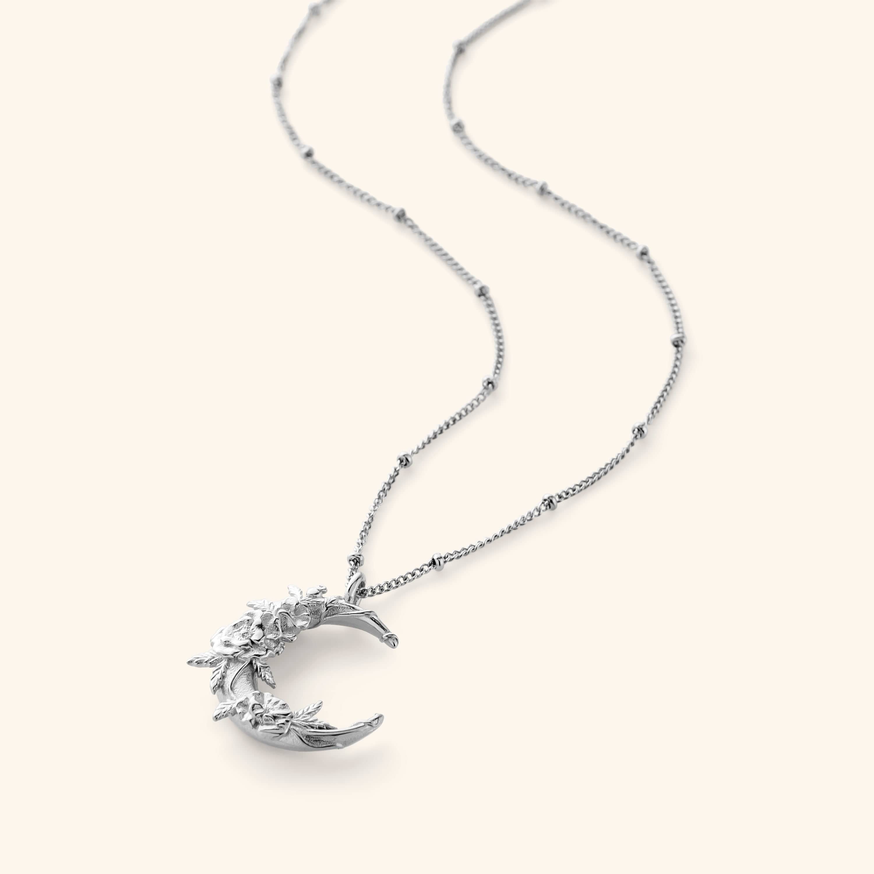Silver necklace. The pendant has poppy flower brought to the hopeful crescent on a thin dotted silver chain.