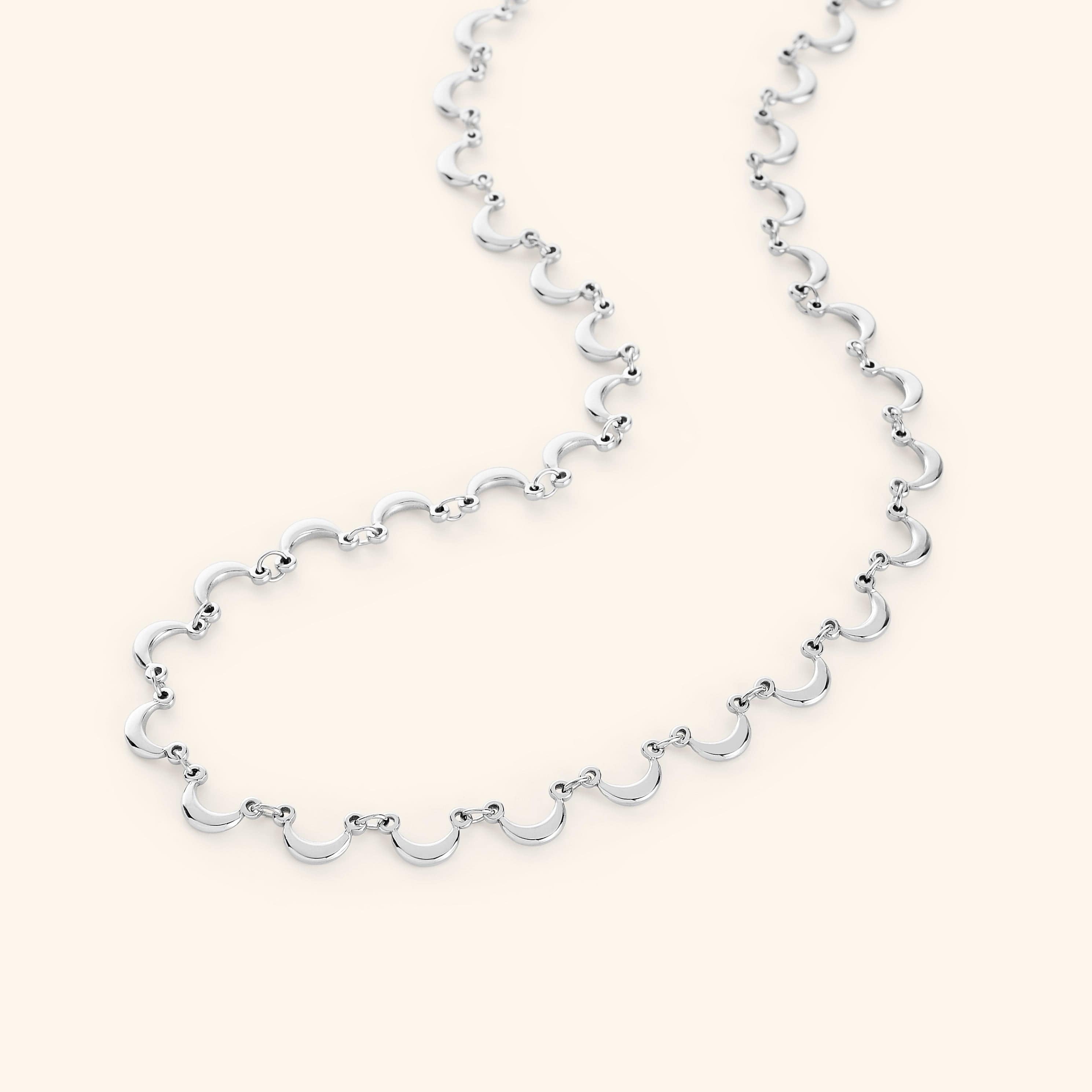 The Skyfall Necklace in a polished silver finish, showcasing a continuous chain of crescent-shaped charms that elegantly mimic the phases of the moon.