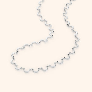 The Skyfall Necklace in a polished silver finish, showcasing a continuous chain of crescent-shaped charms that elegantly mimic the phases of the moon.