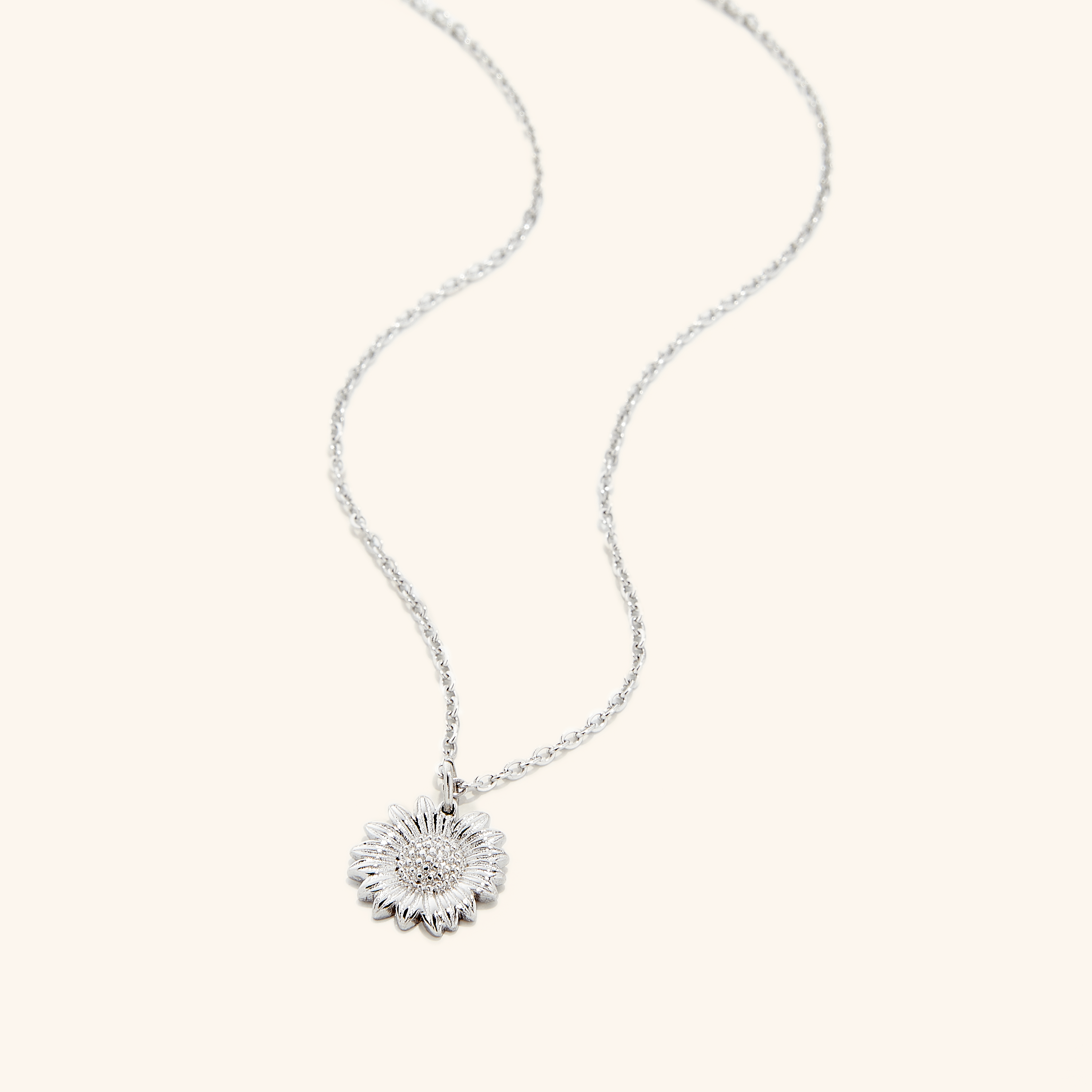 An silver necklace that features a sunflower shaped pendant.