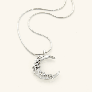 The Jasmine Crescent Necklace in a polished silver finish, showcasing a crescent pendant with detailed jasmine vine engravings, hanging from the Harmony Chain.