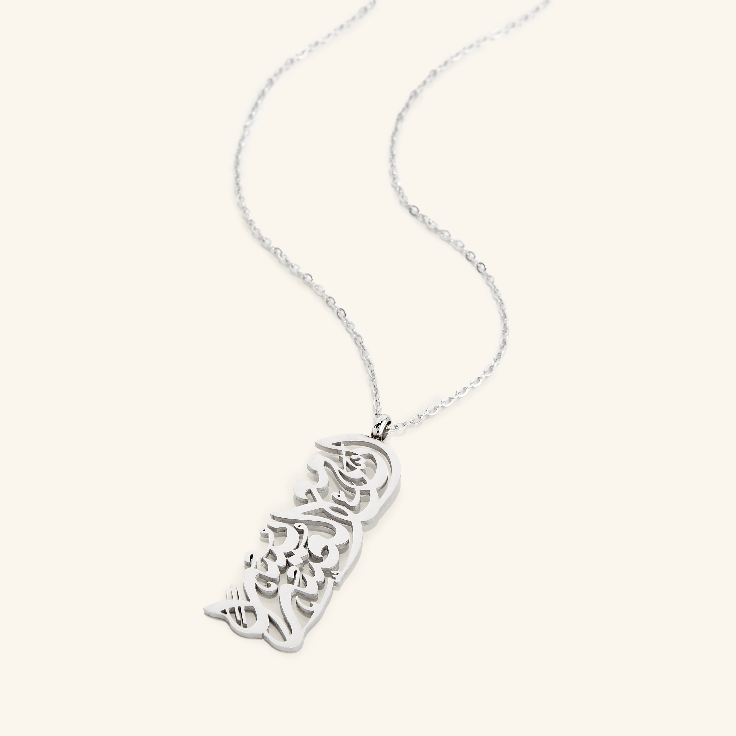 The "With Hardship Comes Ease" Calligraphy Necklace in a polished silver finish. The rectangular pendant displays the same Arabic verse, offering a sleek and timeless design.
