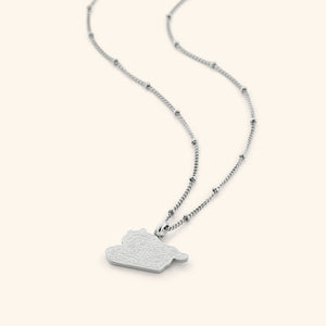 The "With Hardship Comes Ease" Map Necklace in a polished silver finish, showcasing a map outline of Palestine with the engraved Arabic inscription "فَإِنَّ مَعَ الْعُسْرِ يُسْرًا" ("Verily, with hardship comes ease"), hanging from a slender silver chain.