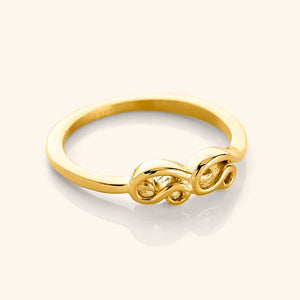 A close-up of the Arabic Mama Ring in 18K gold plating. The ring features the Arabic word Mama in arabic calligraphy, with the Meem and Alif wrapping around to meet in the center, suspended from a gold band.