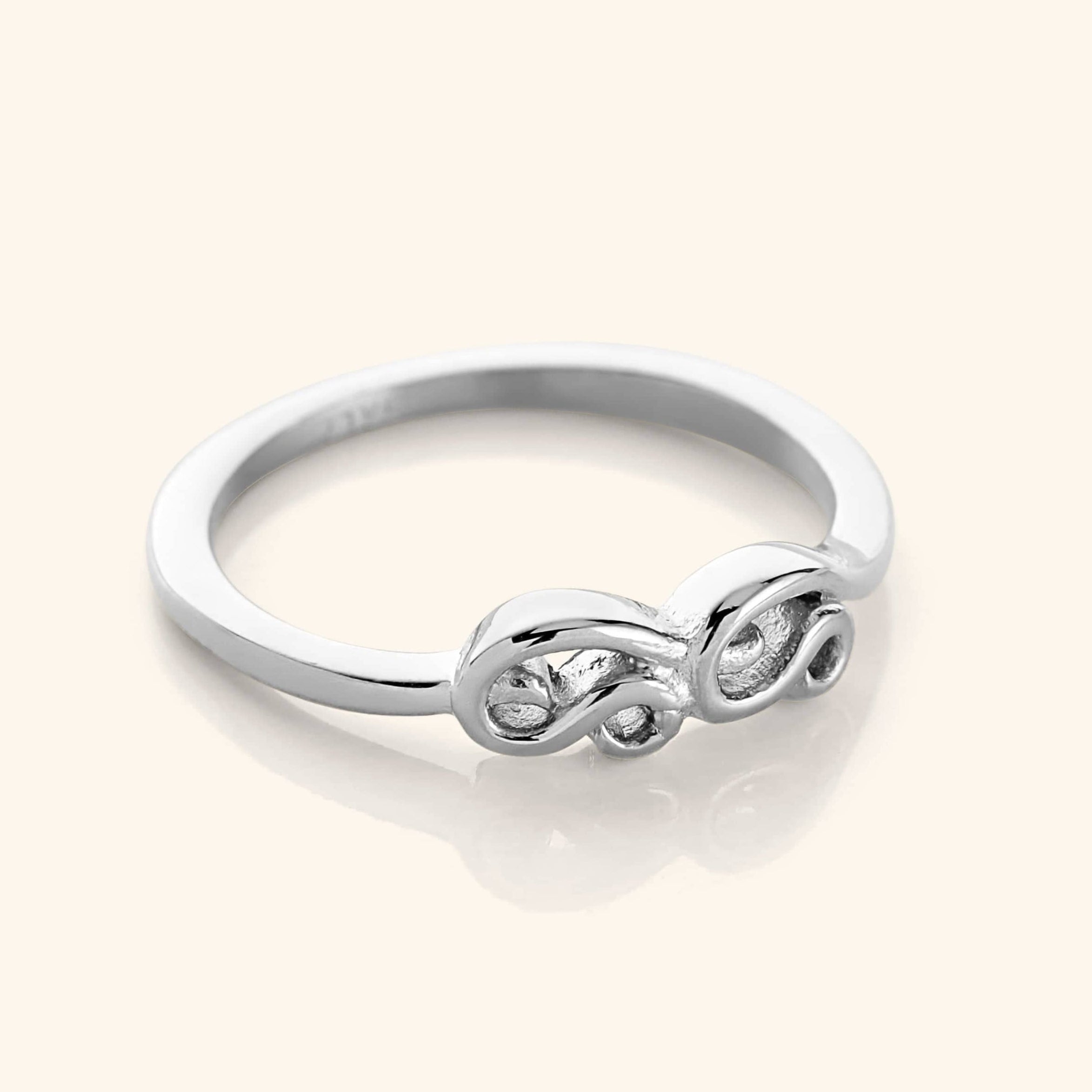 A close-up of the Arabic Mama Ring in silver. The ring features the Arabic word Mama in arabic calligraphy, with the Meem and Alif wrapping around to meet in the center, suspended from a gold band.