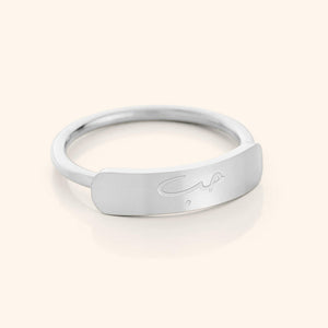 Close-up of a slim silver ring with a rectangular bar centerpiece engraved with the Arabic word meaning "love," shown on a plain background.