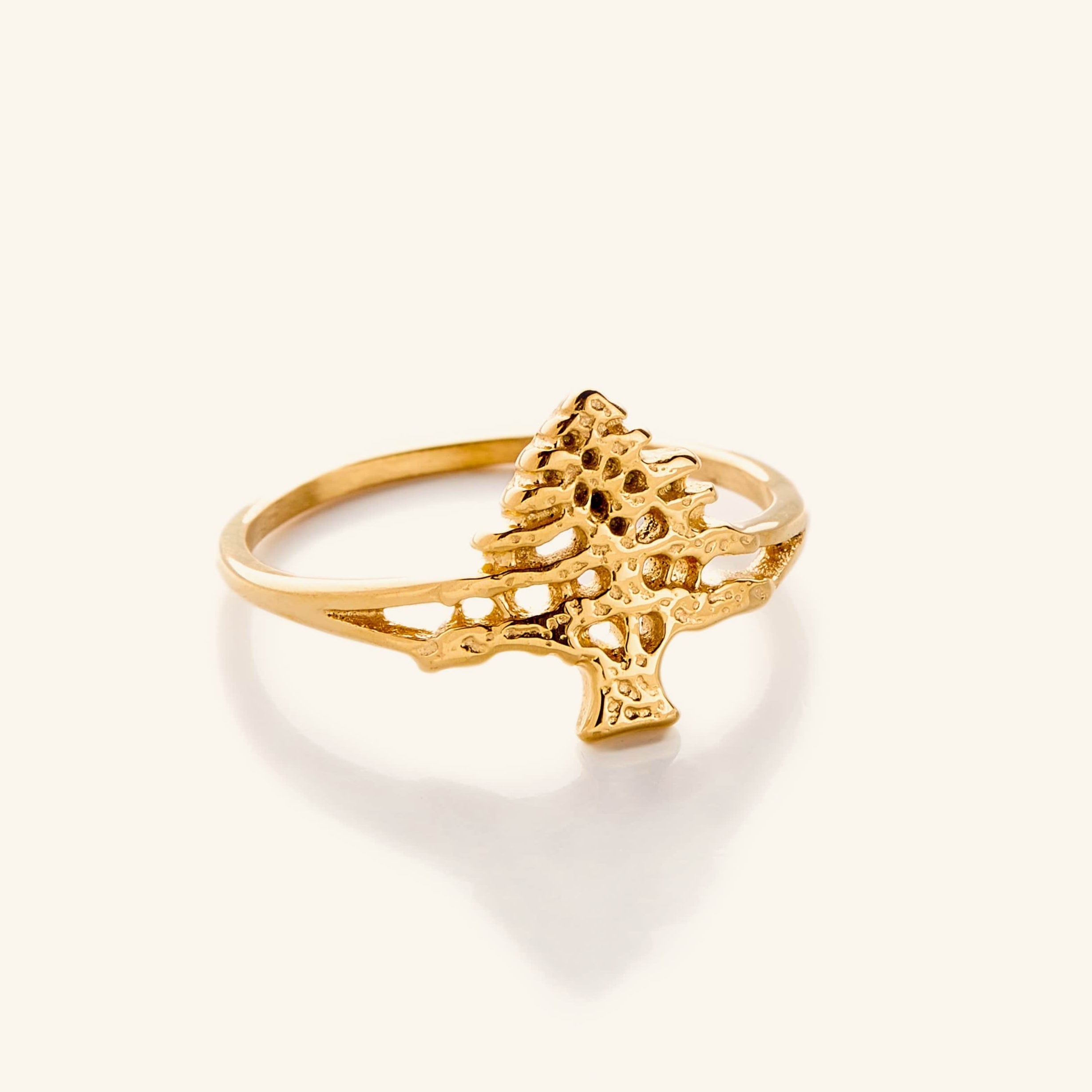 Gold ring featuring a detailed cut-out design of the Cedar of Lebanon tree, with textured branches and an open structure on a slim band, shown against a neutral background.