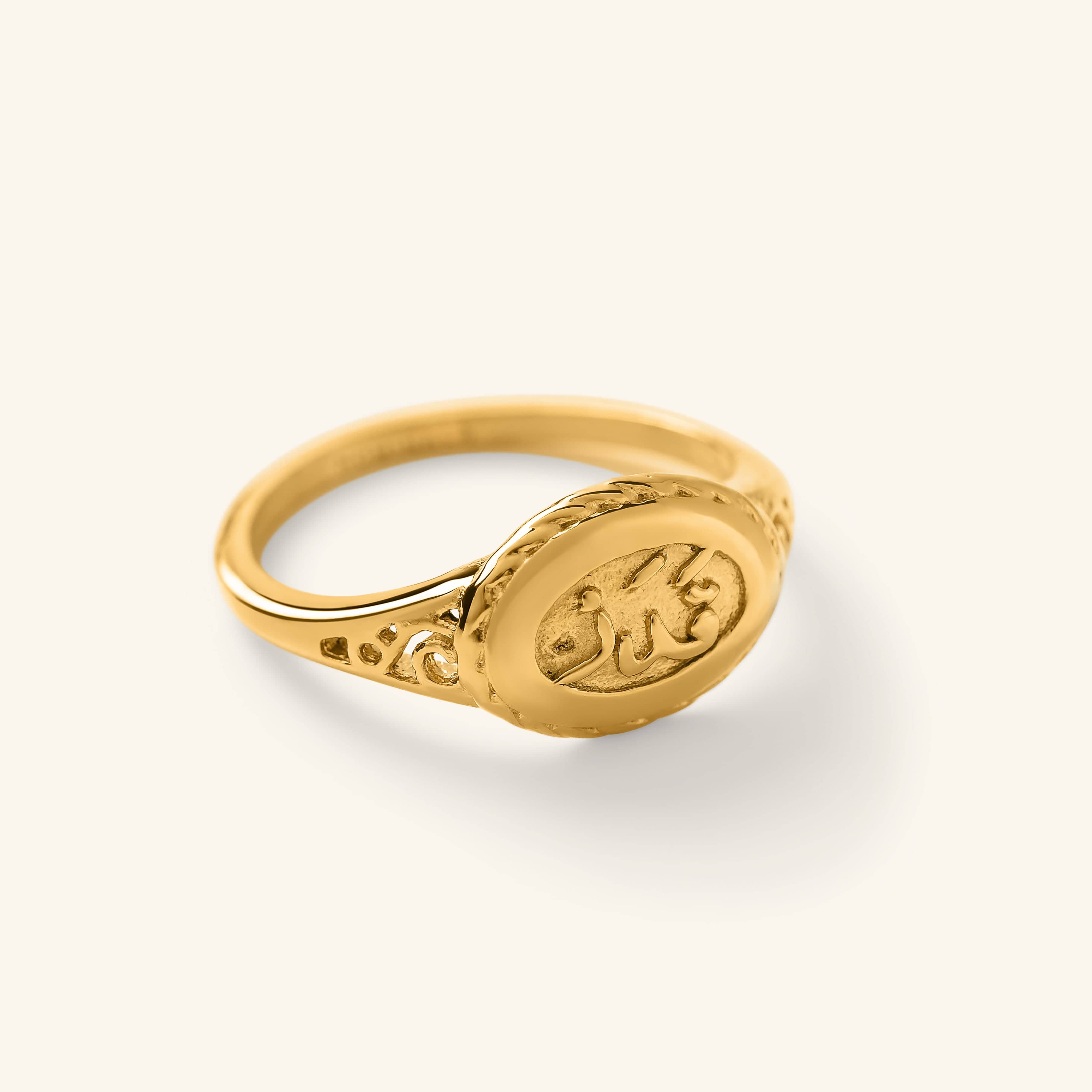 Gold ring with an oval face engraved in Arabic calligraphy, reading “Qadr” (destiny). The band features delicate, cutout detailing along the sides.