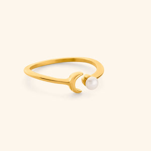 Gold ring with a pearl and moon design on a light background.