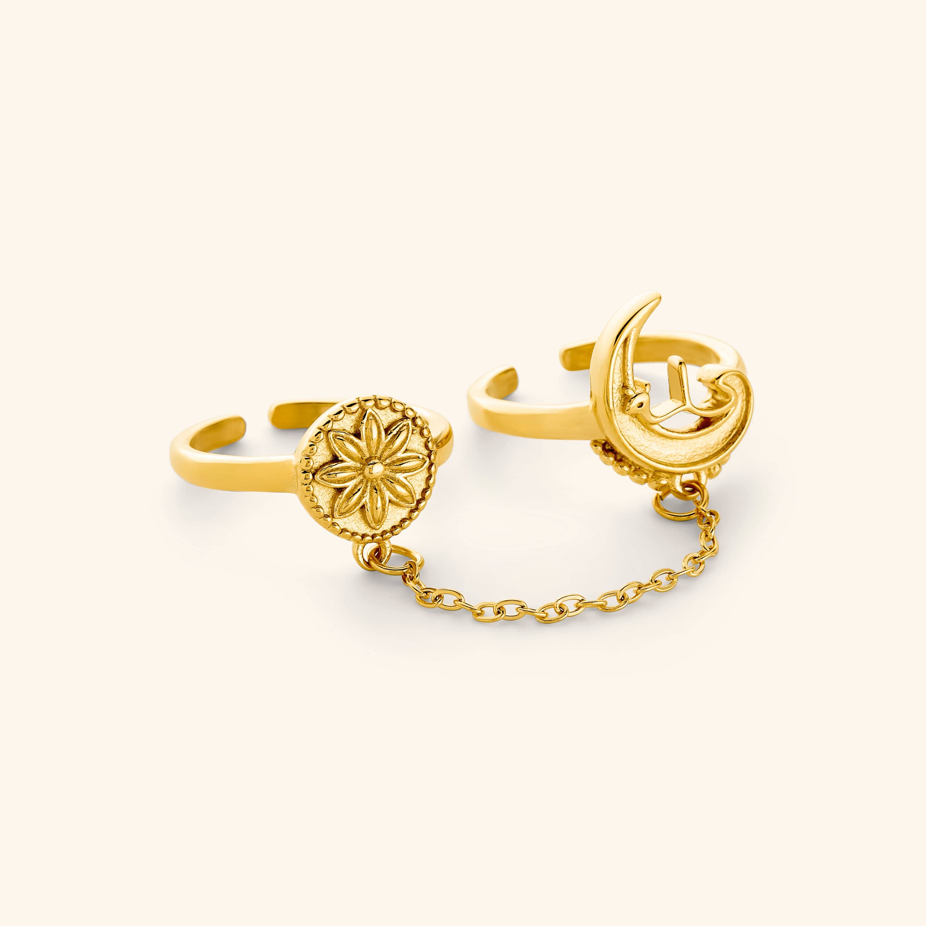 A set of two 18K gold plated rings connected by a thin chain: one ring is carved with a crescent and رحلة (journey) in Arabic, the other stamped with a floral coin.