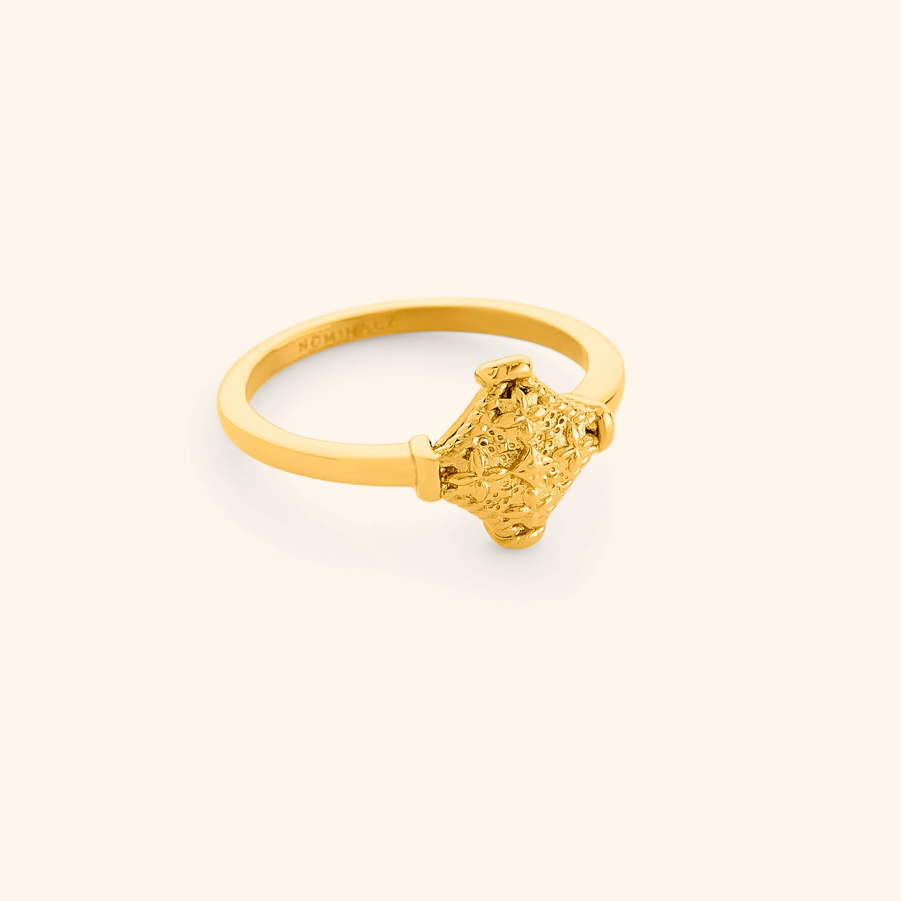 Gold kitework ring featuring a raised, textured centerpiece.