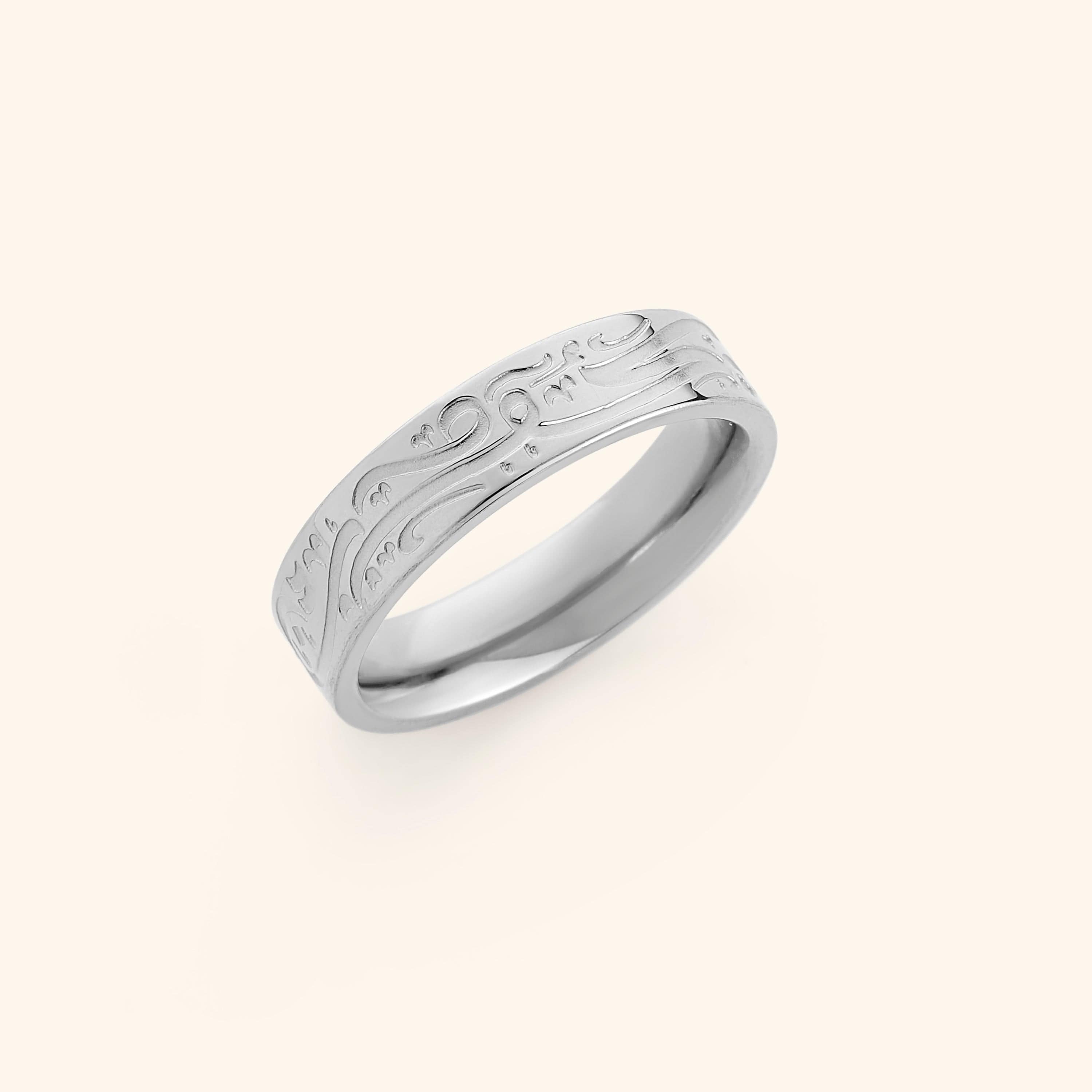 Silver ring with engraved Arabic calligraphy meaning “Be, and it is,”.