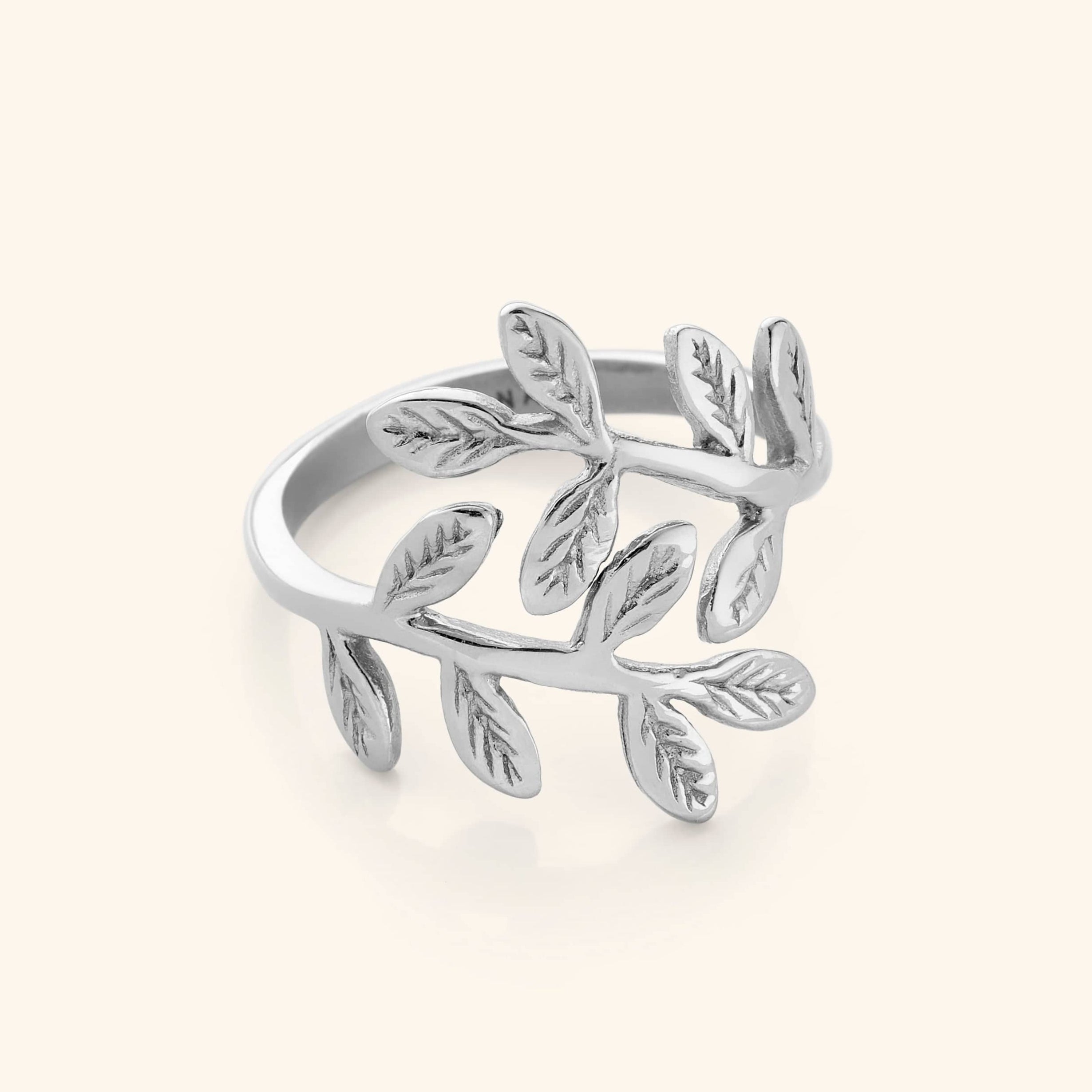 Close-up of a silver ring shaped like intertwining olive branches with engraved leaf details.