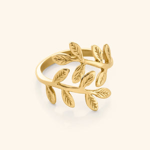 Close-up of a gold ring shaped like intertwining olive branches with detailed leaves engraved on each side.
