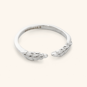 The ring displayed in a polished silver finish, highlighting the intricate leaf details and the open band structure.