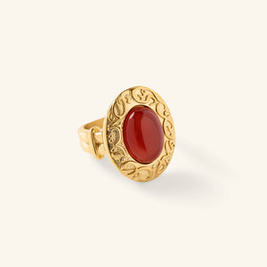 Gold ring with an oval red stone centered inside an engraved bezel featuring arabic calligraphy.