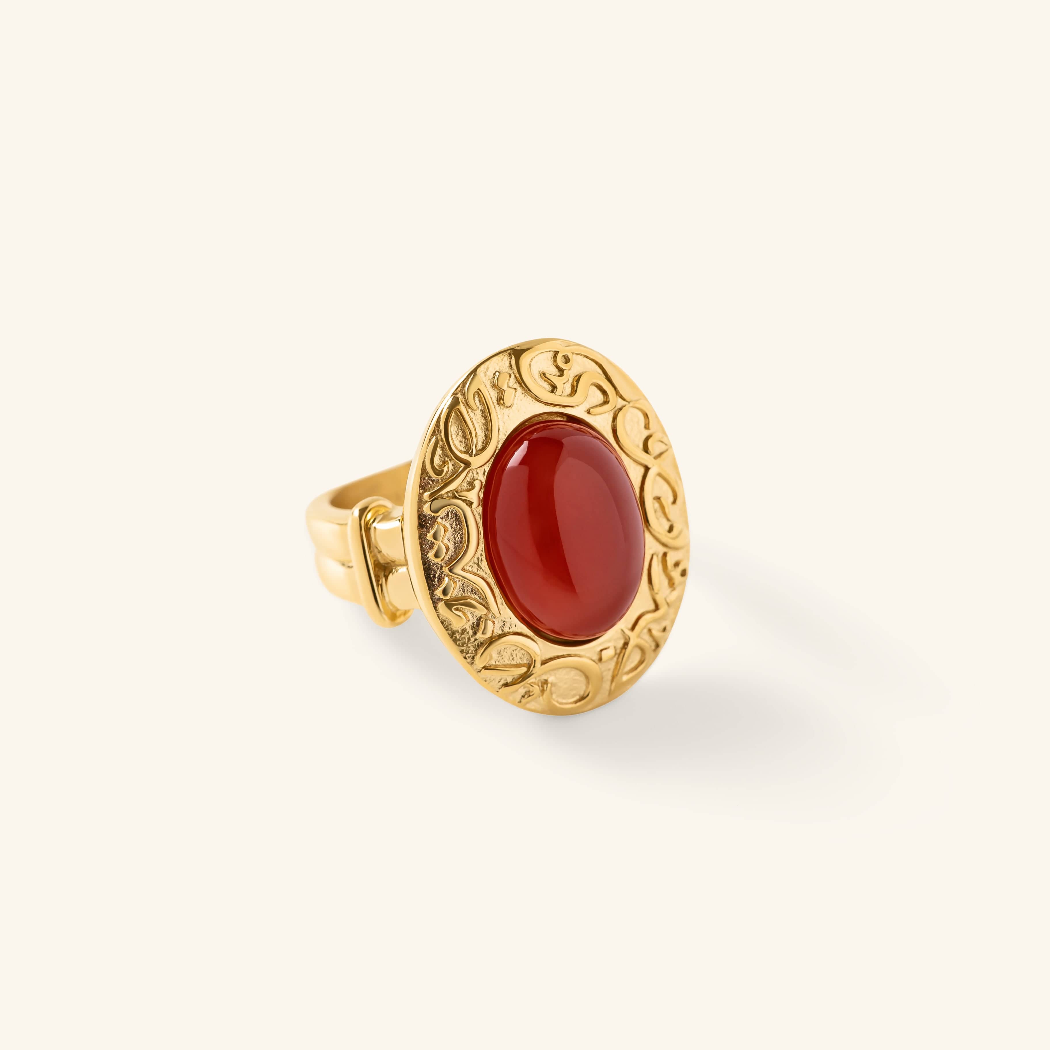 Gold ring with an oval red stone centered inside an engraved bezel featuring arabic calligraphy.