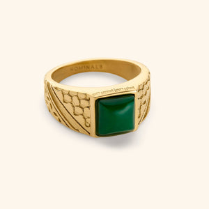 18k Gold plated ring featuring keffiyeh's fishnets and trade route lines and a subtle engraving on the bezel that reads "from the river to the sea" in Arabic Calligraphy with a green onyx ring on a white background.
