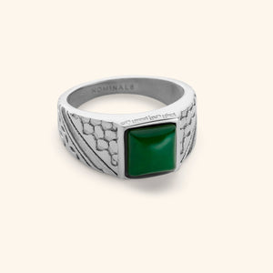 Silver ring featuring keffiyeh's fishnets and trade route lines and a subtle engraving on the bezel that reads "from the river to the sea" in Arabic Calligraphy with a green onyx ring on a white background.
