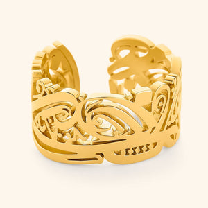 Gold Ease ring with intricate Arabic calligraphy cutout design, wide band with smooth polished edges, photographed against a light background.