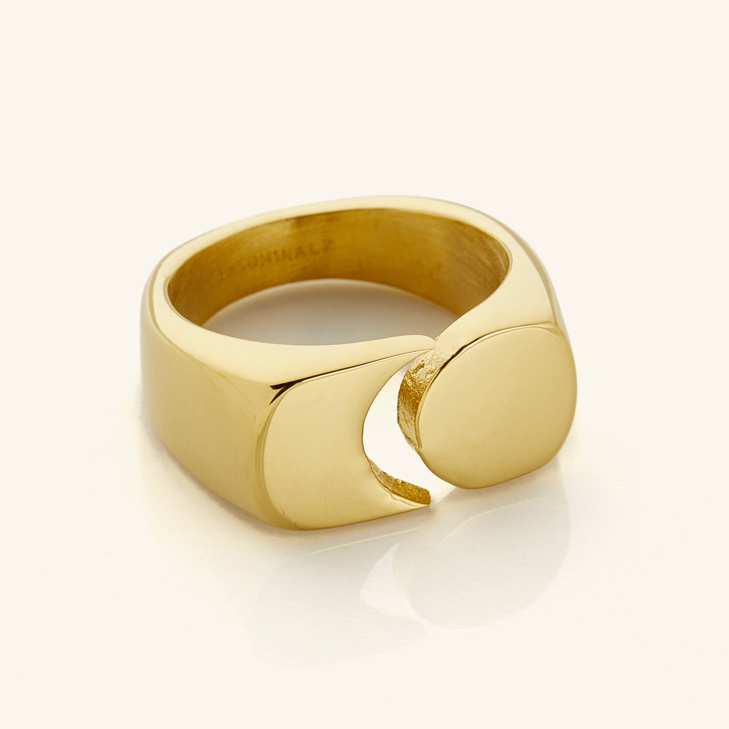 Gold Phases Ring shown close-up on a neutral background, featuring a thick band with a circular disc opposite a crescent cut-out design.