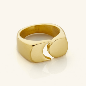 Gold Phases Ring shown close-up on a neutral background, featuring a thick band with a circular disc opposite a crescent cut-out design.