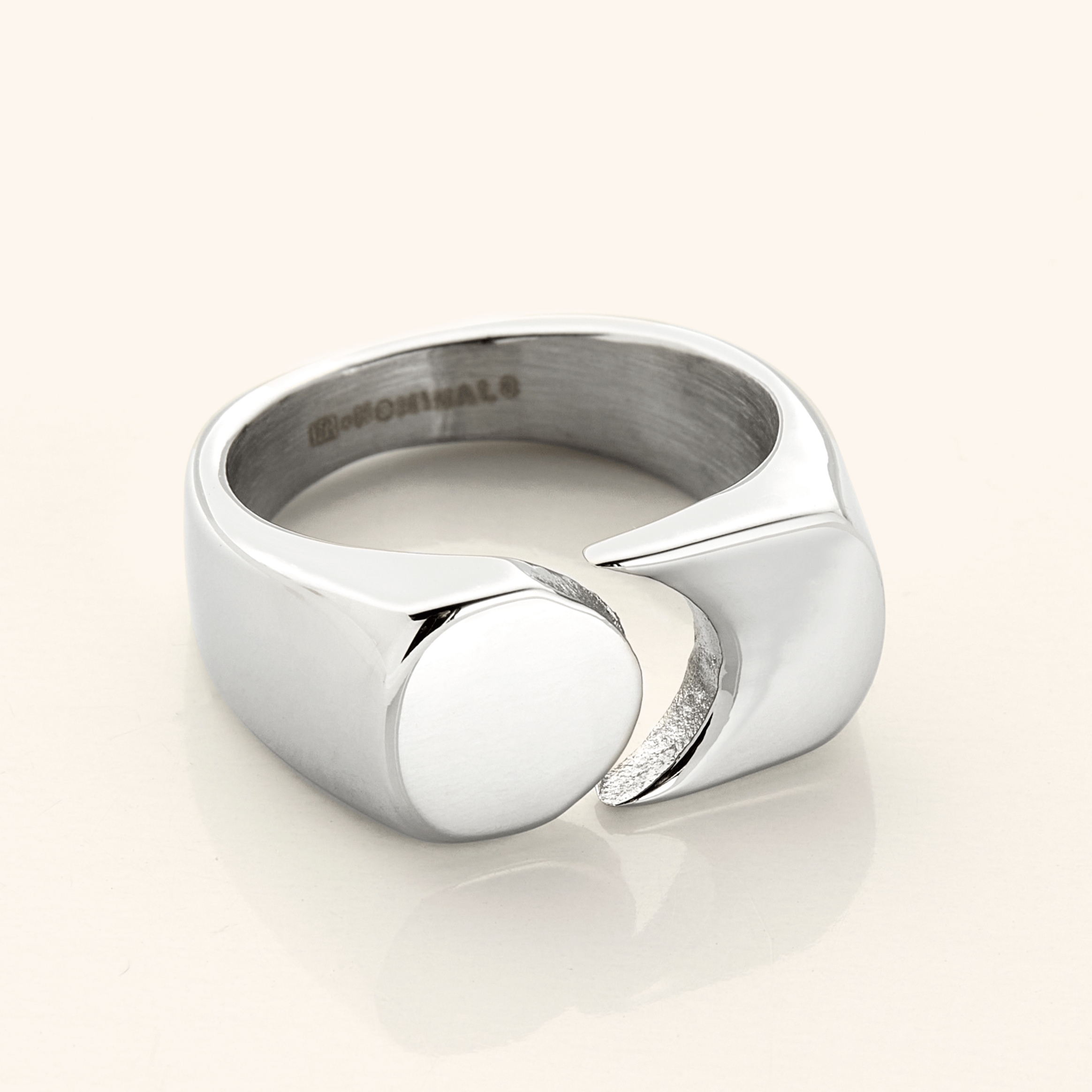 Silver Phases Ring shown close-up on a neutral background, featuring a thick band with a circular disc opposite a crescent cut-out design.